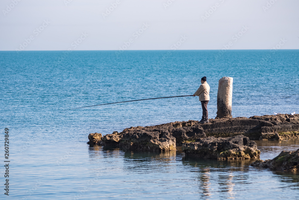 fishermen on the seashore waiting for the catch of the day with their fishing rods