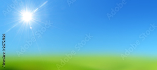 blue sky with sun on a lawn of green grass 