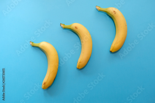 Three bananas on a blue background, top view