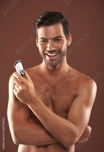 Young smiling guy staying with shaver in hand