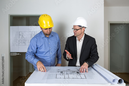Der Architekt erklärt dem Bauherren Details des Bauplans und zeigt ihm die Planbereiche
