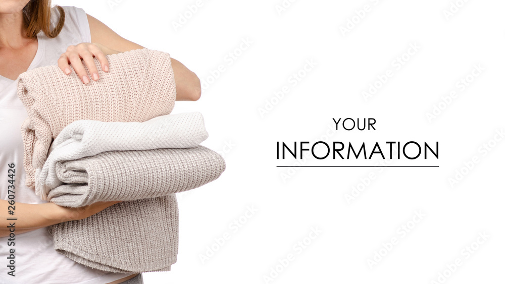 Fototapeta premium stack of sweaters jeans in the hands of a woman pattern on a white background. Isolation