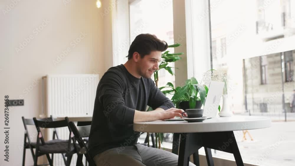 Young hipster businessman working on laptop in cafe and drinking coffee Young hipster businessman working on laptop in cafe and drinking coffee