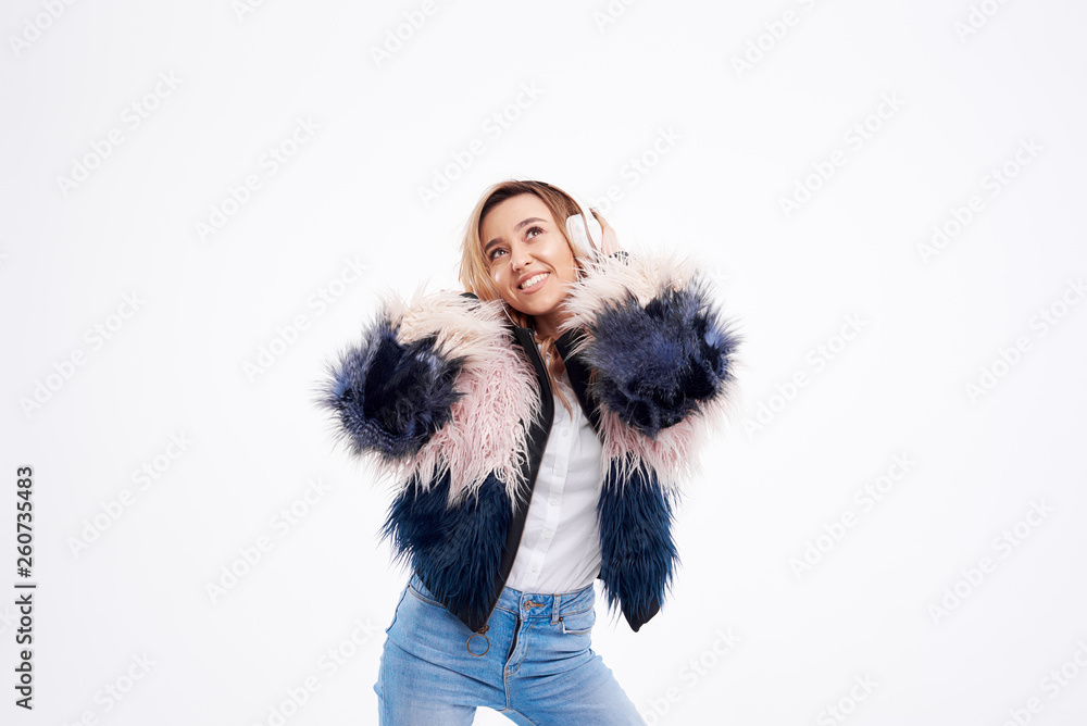 beautiful redhead woman in fur coat and white headphones listens to music and dancing on white isolated background beautiful redhead woman in fur coat and white headphones listens to music and dancing on white isolated background