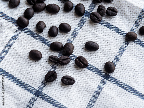 Close up roasted coffee beans on white-blue grid tablecloth. Coffee concept.