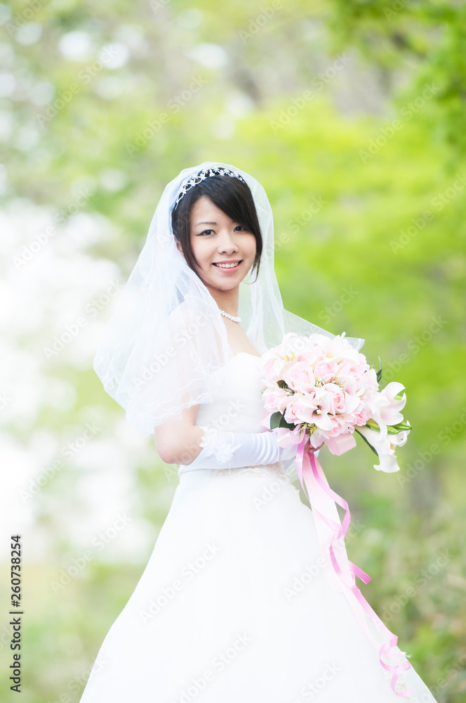新緑の中でブーケを持ち微笑む花嫁 新緑の中でブーケを持ち微笑む花嫁