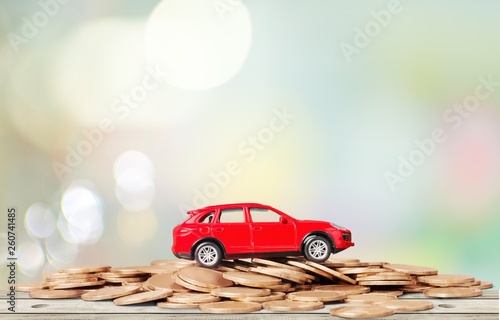 Golden coins and toy car on background
