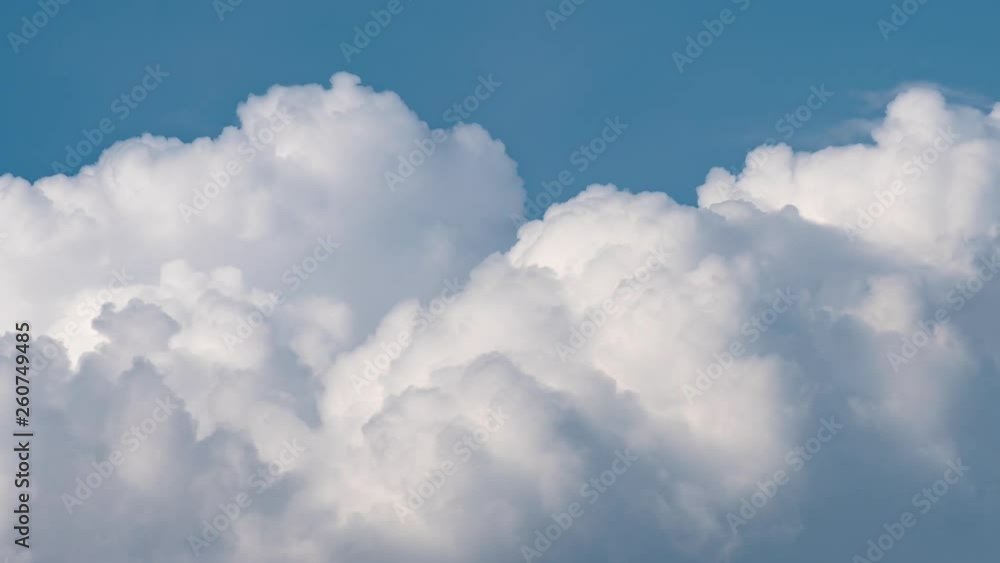 Time Lapse - beautiful white fluffy clouds soar over a deep blue background. Cloudscape with spring or summer clouds moving fast over blue sky day - close-up. Time Lapse - beautiful white fluffy clouds soar over a deep blue background. Cloudscape with spring or summer clouds moving fast over blue sky day - close-up.
