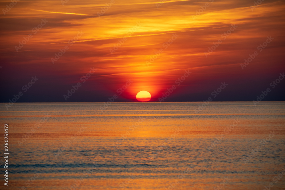 Obraz premium orabge colored sunset over calm sea beach water fields