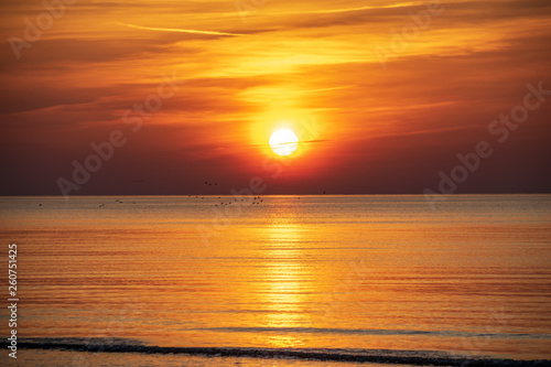 orabge colored sunset over calm sea beach water fields © Martins Vanags