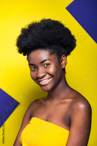 Smiling pretty african american woman looking at camera on yellow and purple