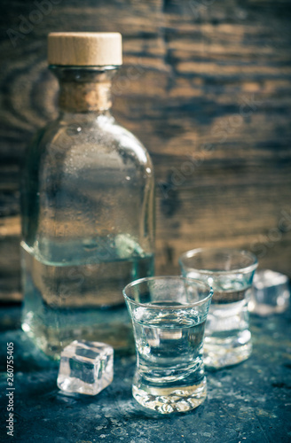 Two shots and a bottle of vodka on wooden background