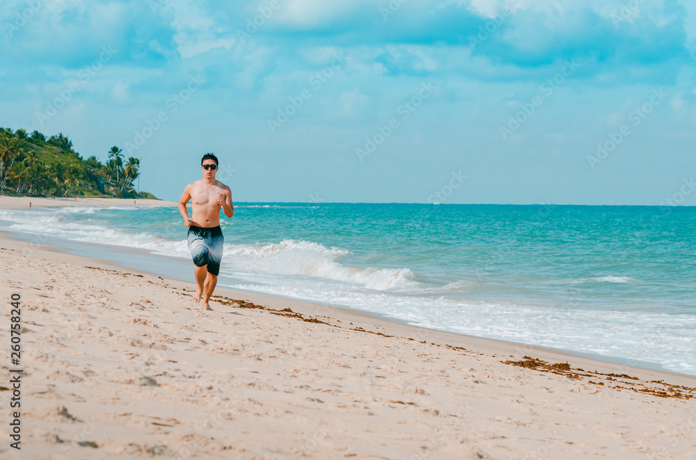 Man running on the beach during summer. Doing cardio exercise on the sand. Photo at Praia de Tabatinga 2, Conde PB Brazil. Man running on the beach during summer. Doing cardio exercise on the sand. Photo at Praia de Tabatinga 2, Conde PB Brazil.