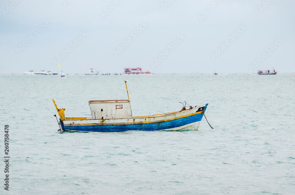 Small boat anchored in the middle of the sea. Small rusty fishing boat.