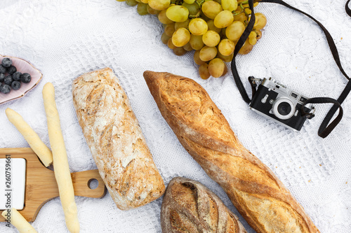 Food lay out on picnic blanket. fresh baked bread, grapes, olives and photocam lay on white blanket. Picnic prepare decoration photo