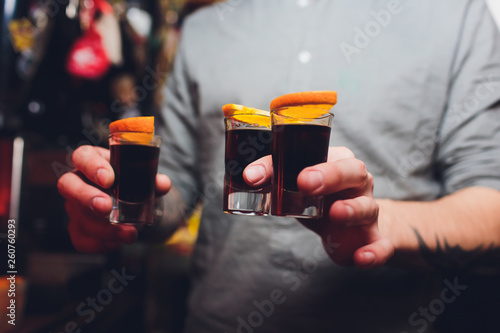 Quadro su tela Jagermeister Shots cocktails with orange hand male.