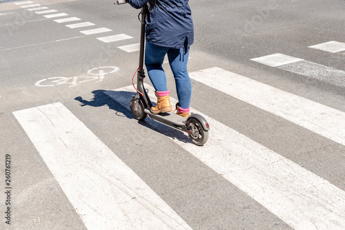 Detail of an electric scooter driven by a woman while waiting her turn to cross a road.