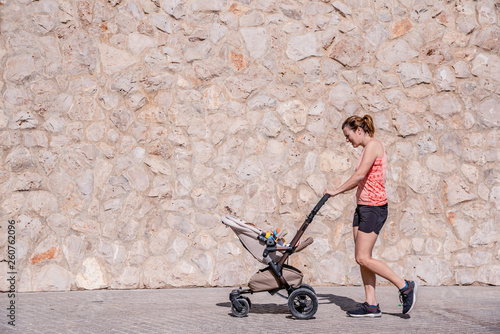 Young mother running with the stroller of her baby to stay in shape after childbirth.