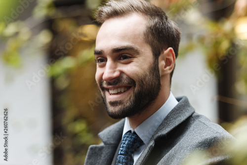Smiling young business man wearing suit walking