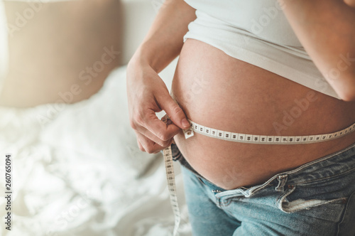 Tablou pe pânză Happy pregnant woman with measuring tape Pregnancy, maternity, preparation and expectation concept