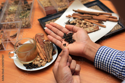 Hand holding dry herbal on a wooden background with all dry herbs ingredients. Herbal teas beverage for chinese or thai traditional alternative medicine therapy. 