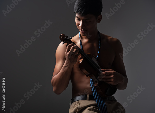 The handsome man holding violin in hands,and press on string,with happy face,model posing with the acoustic instrument,art tone,blurry light around