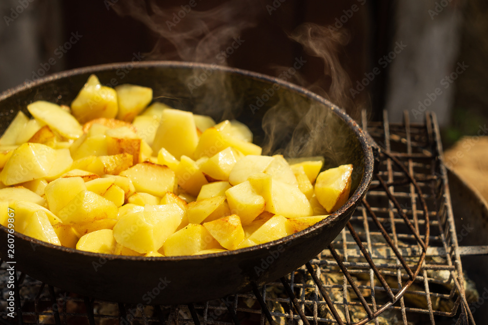 Potatoes fried in a frying pan on a grill Potatoes fried in a frying pan on a grill