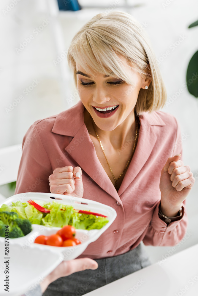 cropped view of man holding takeaway box with vegetables near excited blonde woman cropped view of man holding takeaway box with vegetables near excited blonde woman