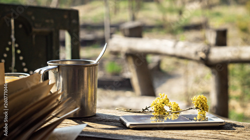 Metal mug, a flowering branch and a telephone on a wooden table