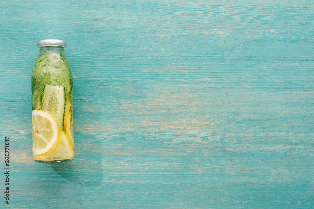Obraz premium top view of detox drink in bottle with fresh lemon and cucumber slices and green mint