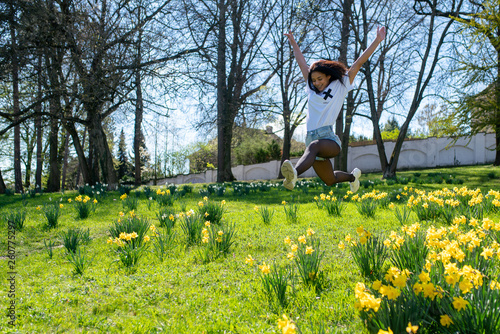 Gl  ckliche junge Frau springt   ber gelbe Blumen