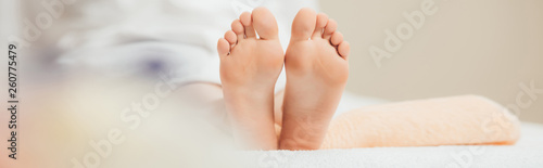 panoramic shot of adult woman lying on beige towel in spa photo
