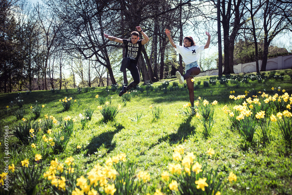 Junges Paar springt über Blumenwiese