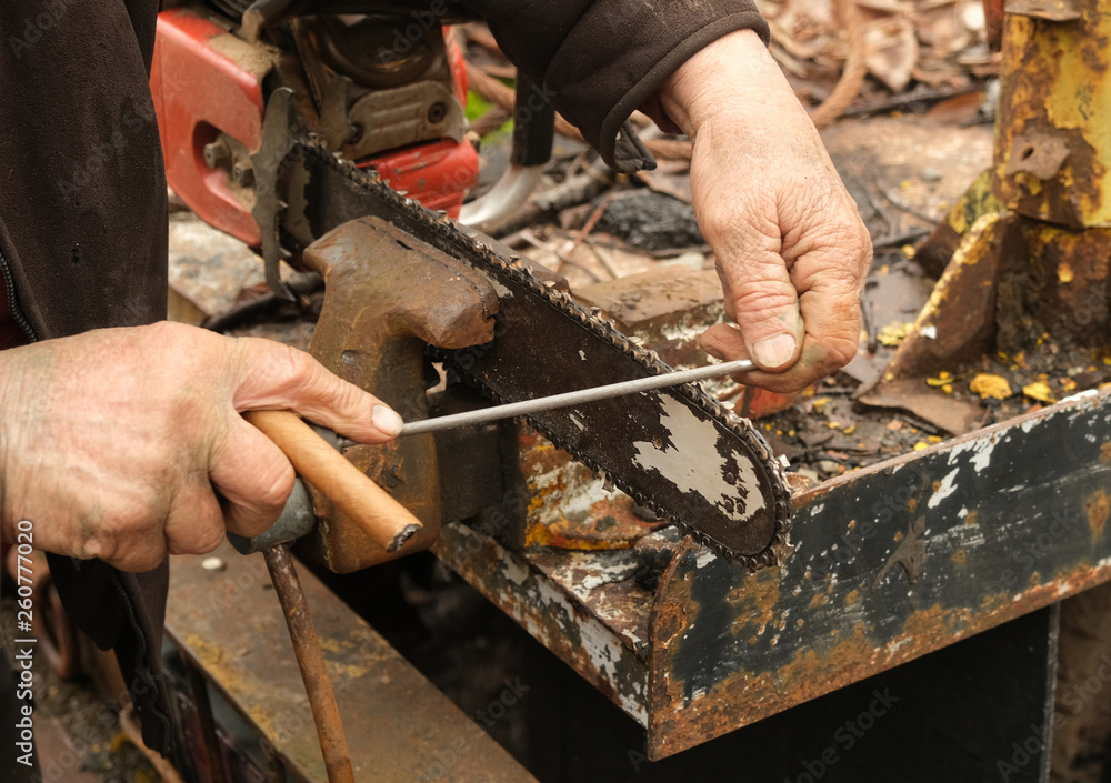 Working man's hands filing a chain saw blade 2 Working man's hands filing a chain saw blade 2