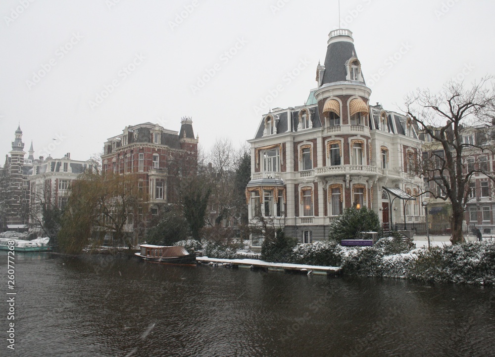Naklejka premium Snowy landscape in Amsterdam with boats and houses