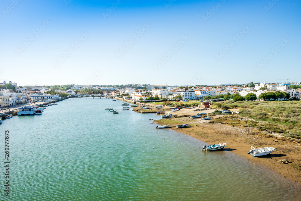 Cityscape fo Tavira with fisherman boats and roman bridge over Gilao river, Portugal