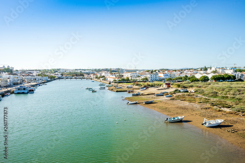 Cityscape fo Tavira with fisherman boats and roman bridge over Gilao river, Portugal