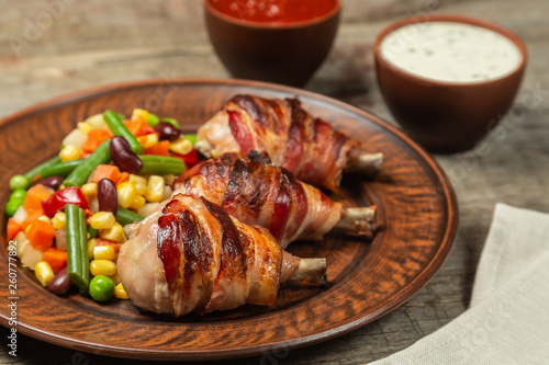 Fried chicken legs wrapped in bacon with vegetables