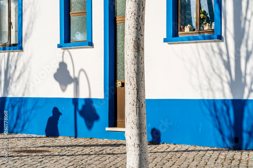Black shadows of people, tree and lantern on traditional house in Tavira, Algarve, Portugal