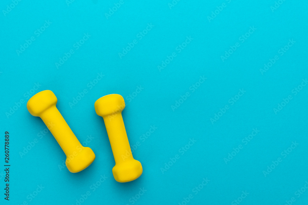 flat lay photo of yellow fitness dumbells over blue backgound with copy space flat lay photo of yellow fitness dumbells over blue backgound with copy space