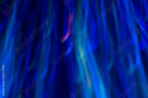 Blurry vertical wavy lines. Multicolor neon lights in motion on dark background. Bokeh lens flare glow.