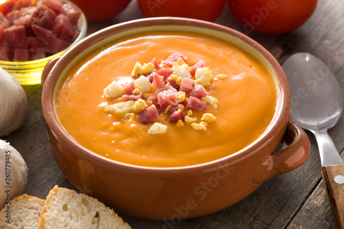 Typical Spanish salmorejo cream with ham and egg on wooden table.  photo