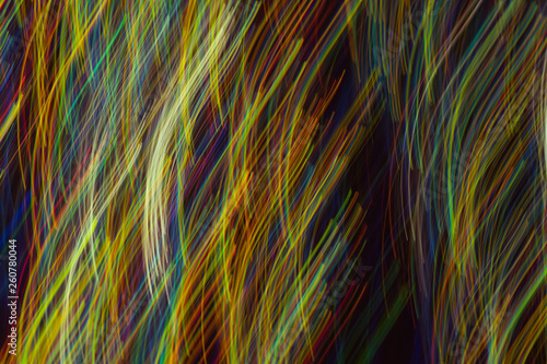 Defocused lights in motion. Blurred vertical multicolor lines on dark background. Lens flare effect.