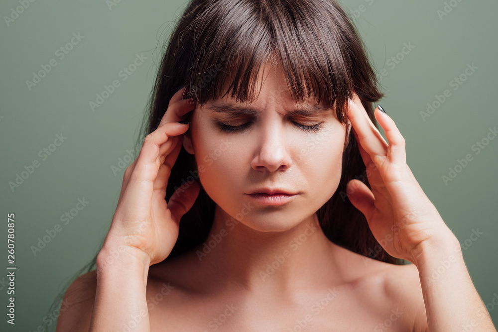Tired young pretty lady. Suffering facial expression. Closeup portrait of emotional brunette woman with hands at her temple. Tired young pretty lady. Suffering facial expression. Closeup portrait of emotional brunette woman with hands at her temple.