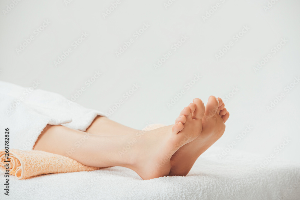 partial view of adult woman lying on beige towel in spa