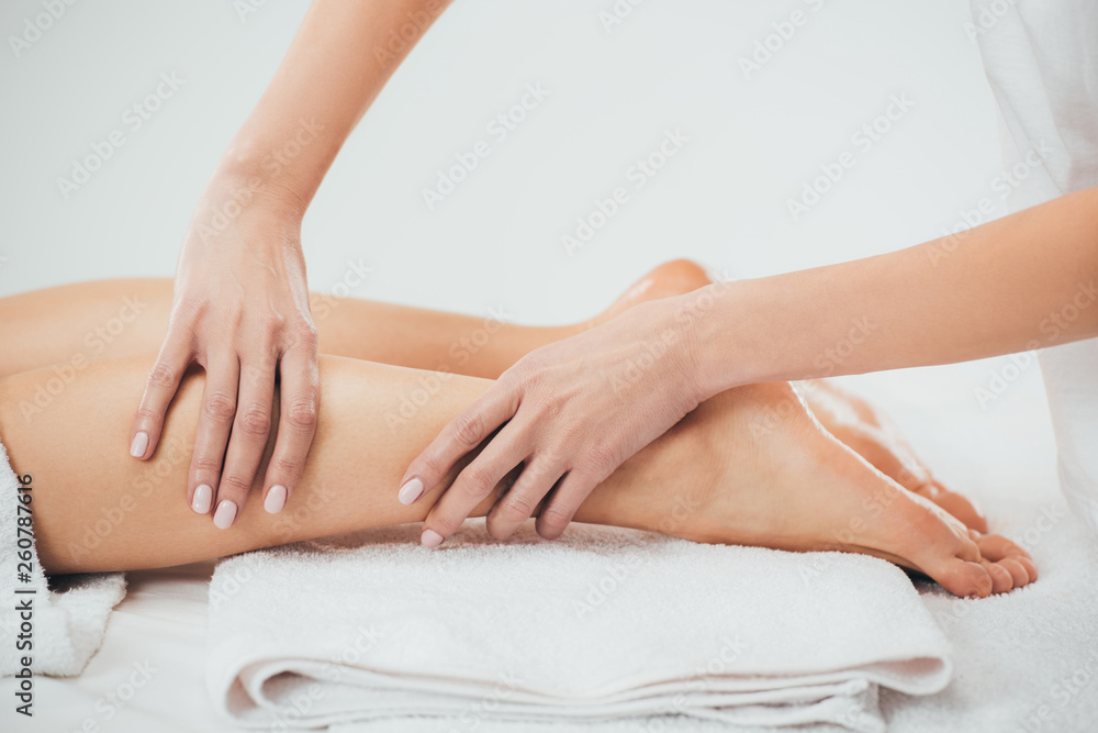 partial view of masseur doing foot massage to adult woman in spa partial view of masseur doing foot massage to adult woman in spa