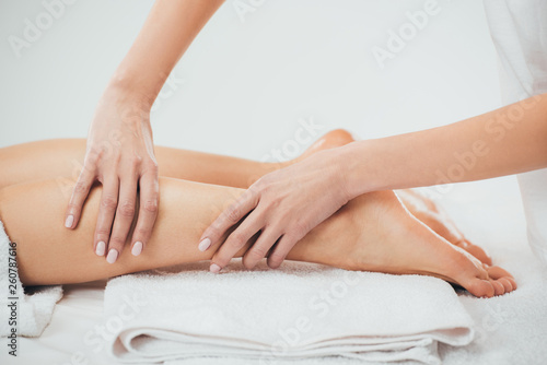 partial view of masseur doing foot massage to adult woman in spa
