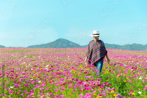 Traveler Asian women walking in outdoor the flower field and hand touch cosmos flower, freedom and relax in the flower meadow. Lifestyle and Vacation Concept
