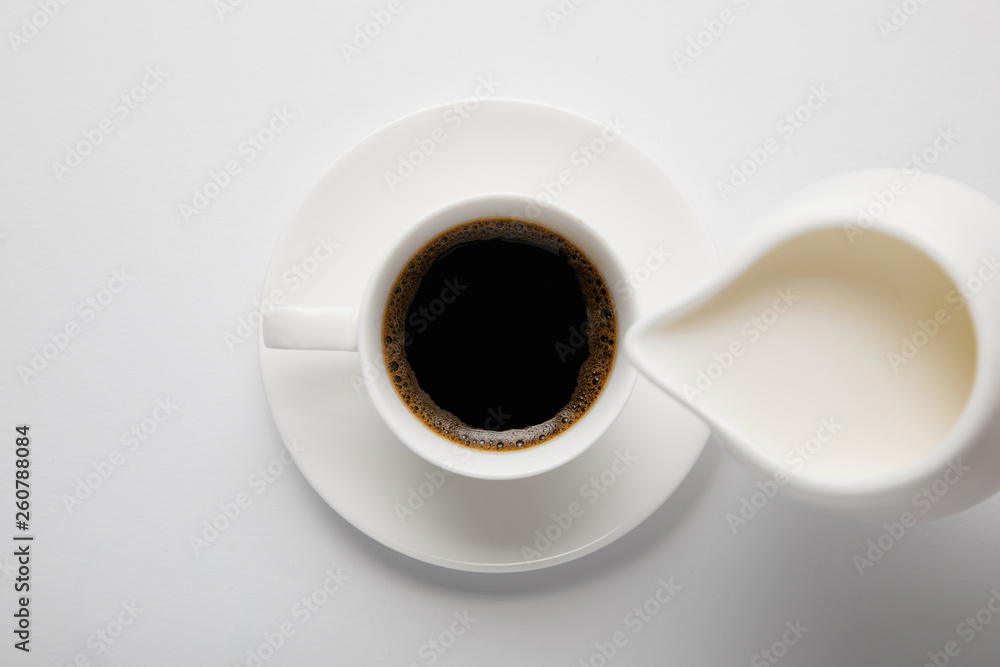 Top view of coffee cup and jug of milk on white Top view of coffee cup and jug of milk on white