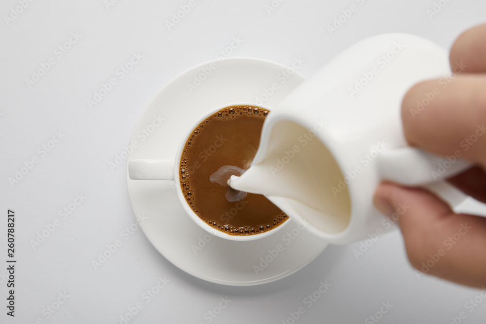 Cropped view of woman pouring milk in coffee on white Cropped view of woman pouring milk in coffee on white